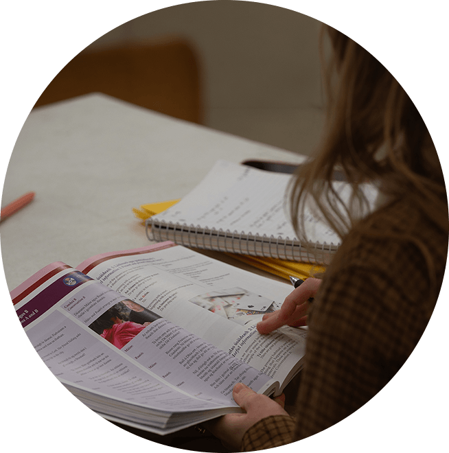 A student looking over a workbook with a notebook on a desk.
