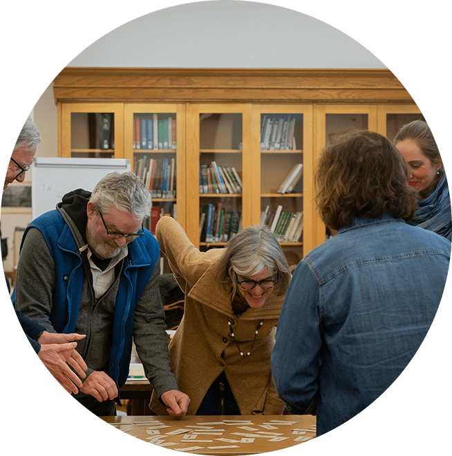 A group of members doing classwork together over a table.