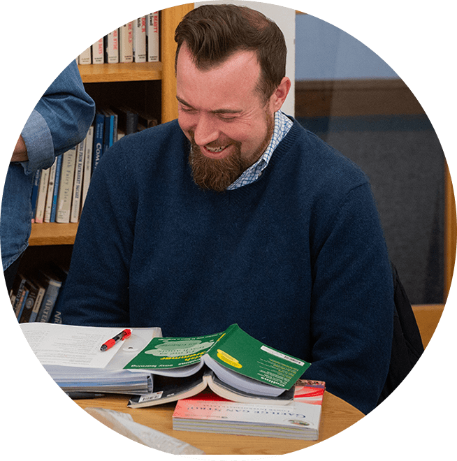 A man sitting at a desk smiling overlooking lesson content.